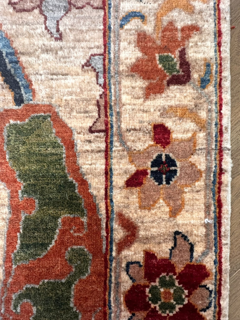 Close-up showing cream pile texture, olive and terracotta motifs and floral border