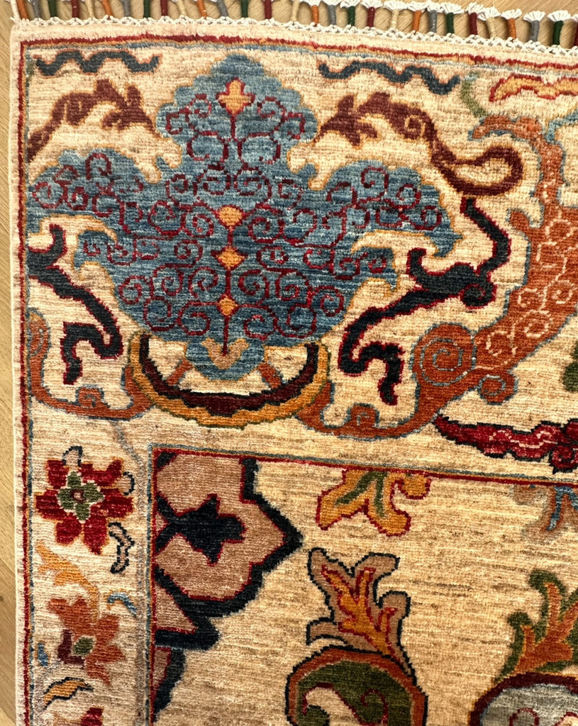 Close-up of blue floral border motif, visible pile fibres and multicoloured fringe