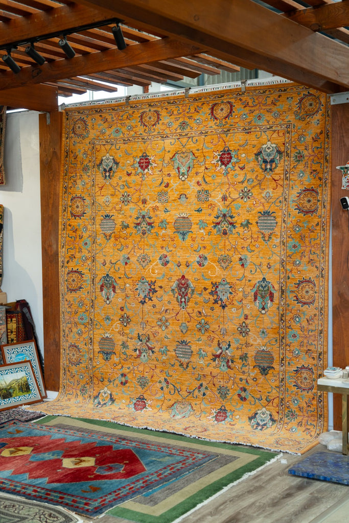 Golden ochre Sultani Chobi rug displayed in the Sama Rugs showroom, showing the full floral pattern and turquoise details