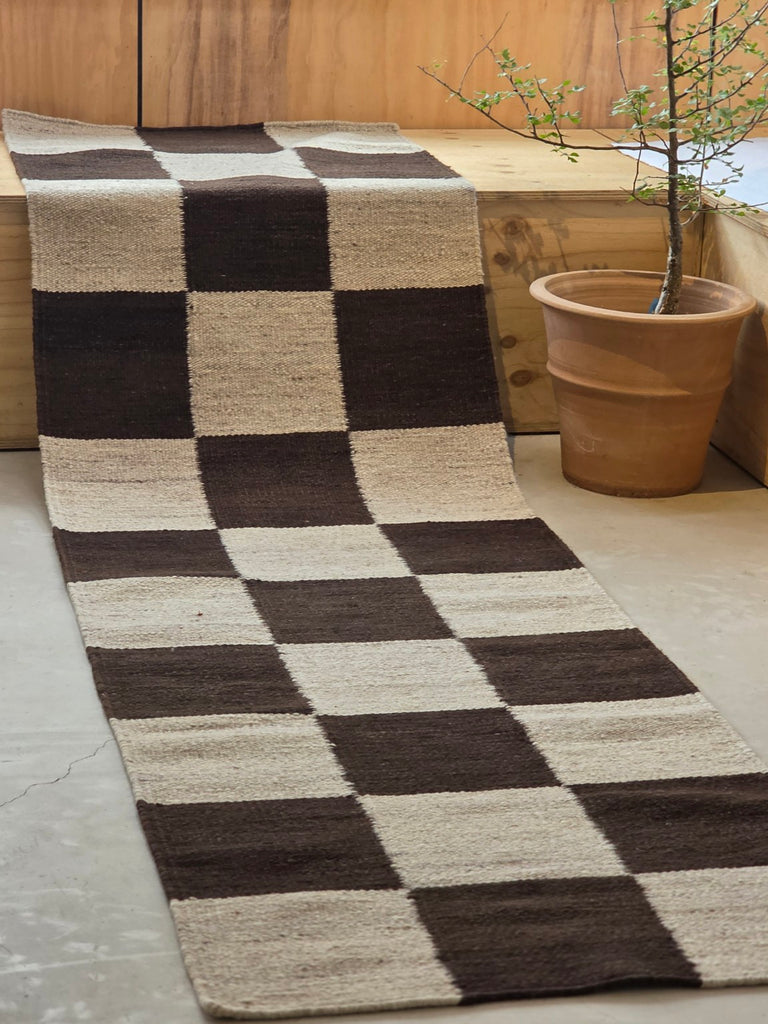 Checkered wool runner draped beside a terracotta planter