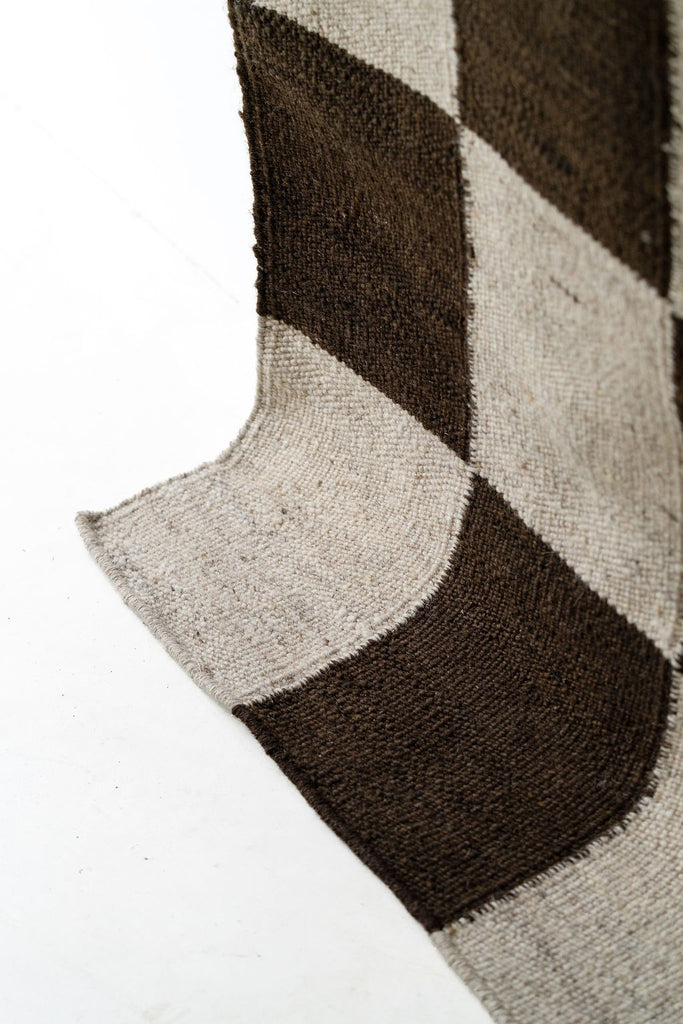 Draped edge and woven texture of the checkered wool rug