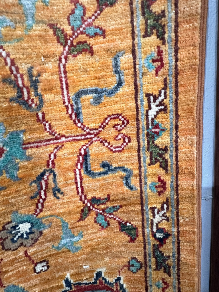 Close-up of burgundy vines and blue foliage showing the golden rug's pile texture